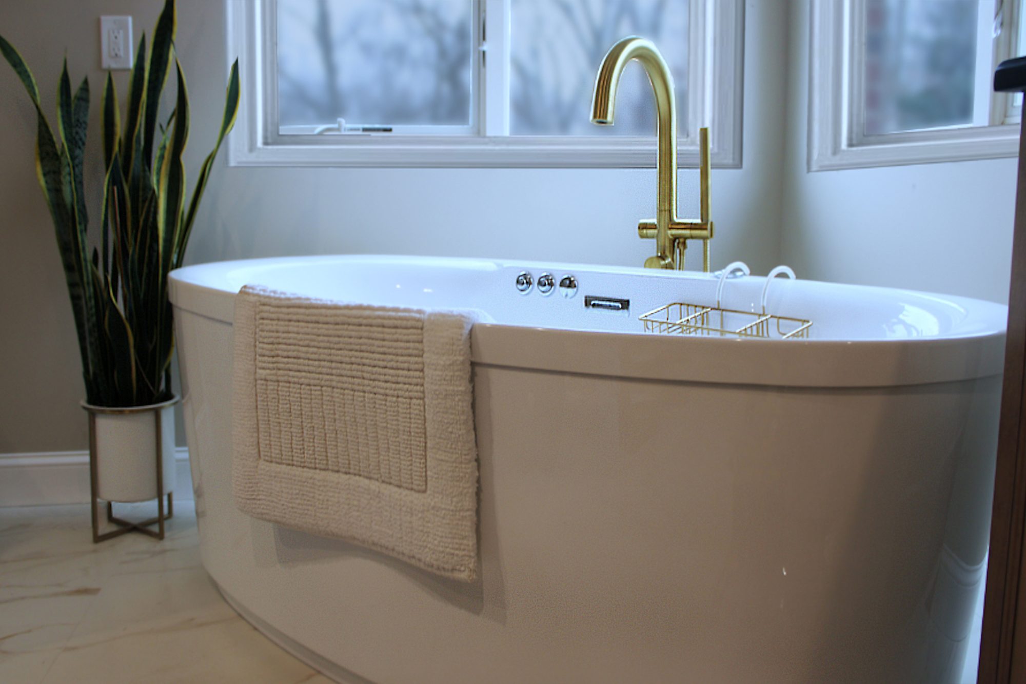 Freestanding tub with a brass floor mount filler and hand shower in a Rochester Hills MI master bathroom remodel