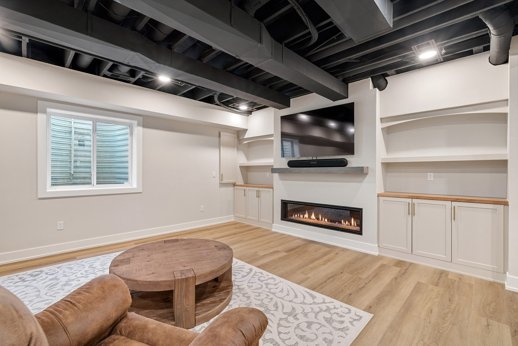 Built in media wall with a 60 inch gas fireplace and Dura Supreme cabinetry in a Birmingham MI basement