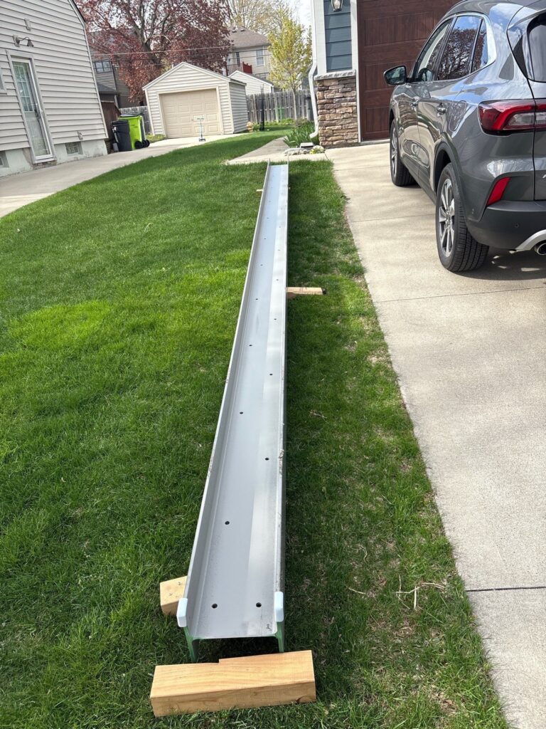 26 foot steel I beam staged on the lawn before installation at a Birmingham MI home remodel